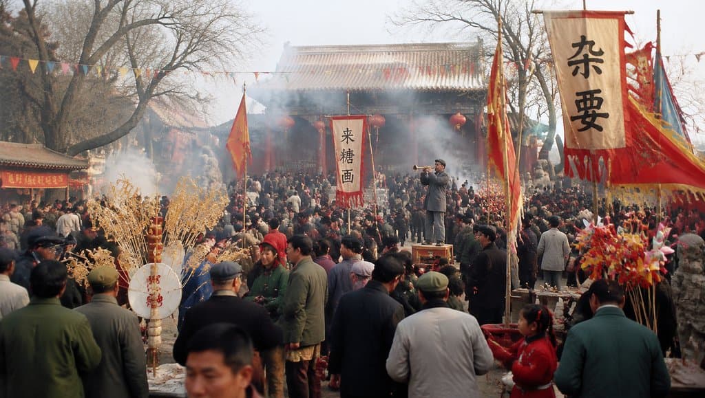 热闹的庙会场景，人群熙攘，彩旗飘扬，糖人风车和杂耍摊点缀其间，充满年代怀旧气息