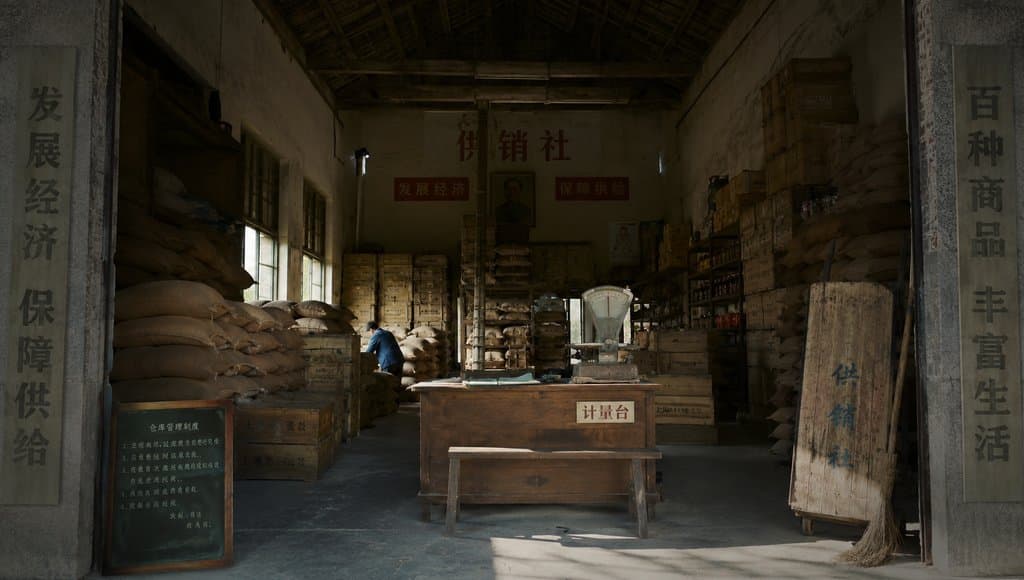 供销社仓库内景，麻袋木箱堆叠，老式磅秤与木质柜台，怀旧写实风格