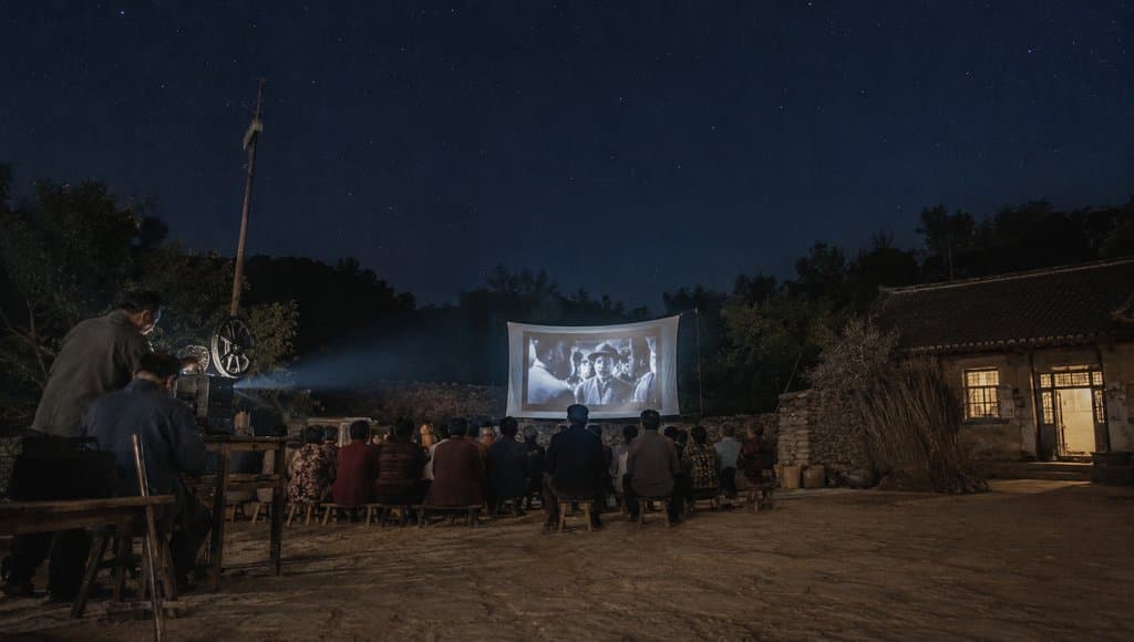 乡村夜场露天电影，人群围坐观看白幕放映，怀旧写实风格