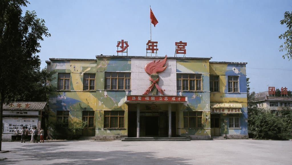 少年宫建筑，彩绘外墙，红领巾雕塑，旗杆飘扬，年代怀旧写实风格