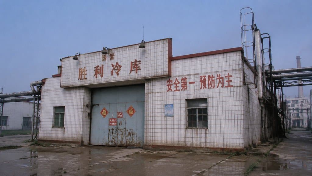 国营胜利冷库，白瓷砖墙面，铁门贴福字，工业管道环绕，怀旧写实风格建筑