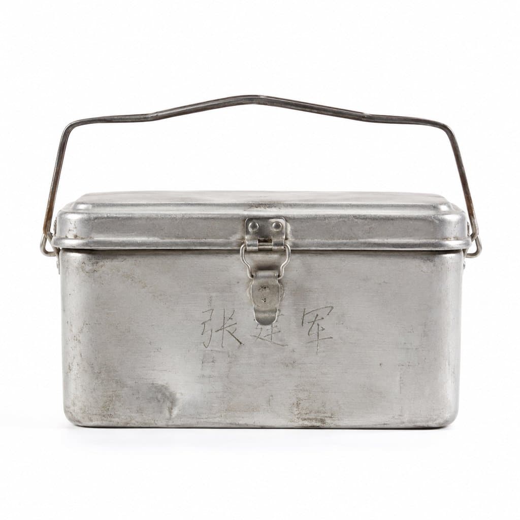 复古铝制饭盒，长方形扣盖设计，表面有磕碰痕迹，手写中文名字，怀旧写实风格