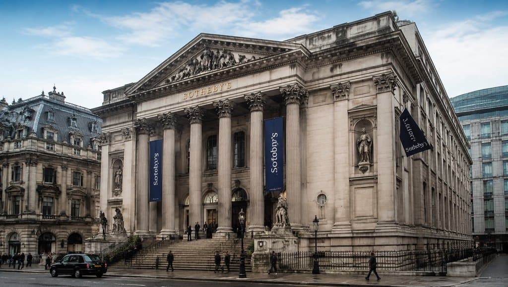 古典风格拍卖行大楼，宏伟立柱与台阶，Sotheby's标志醒目，写实建筑细节
