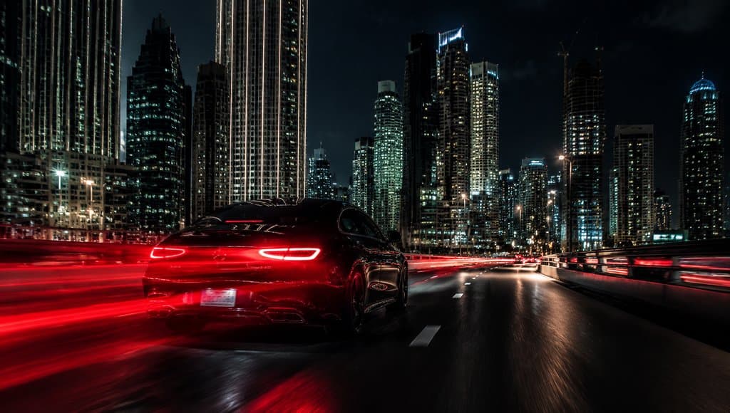 夜景都市中行驶的黑色豪车，尾灯红光拖曳，高楼林立，速度感十足的写实特效图