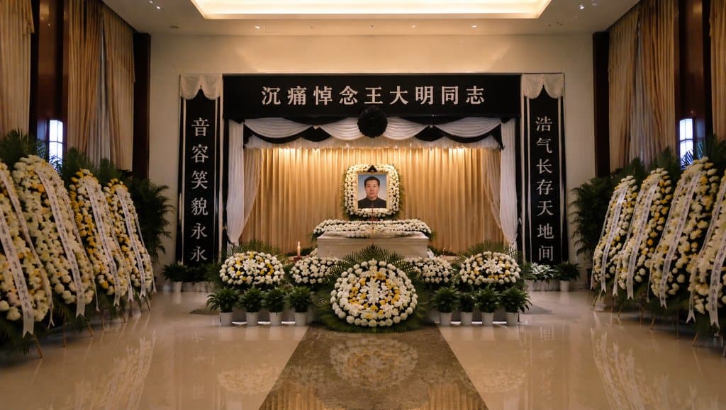 殡仪馆告别厅内景，遗像前摆放花圈与白幛，庄严肃穆的现代都市写实场景