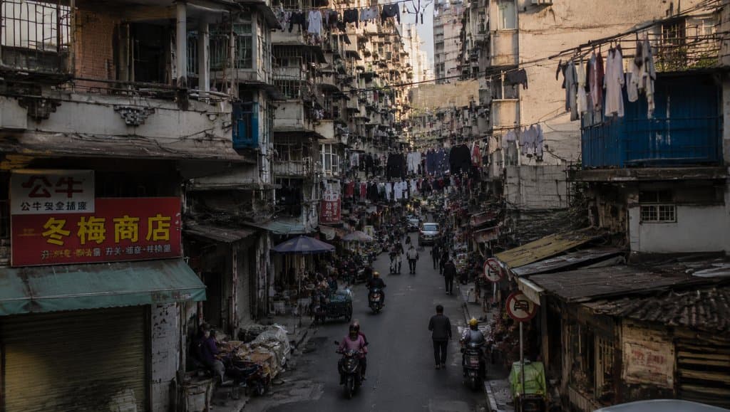 城中村街巷，握手楼林立，空中挂满晾衣，电线交错，现代都市写实场景