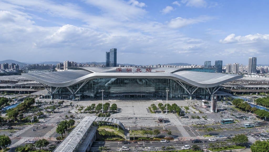 深圳北站现代高铁站建筑，流线型屋顶与玻璃幕墙设计，前方广场开阔，背景城市天际线清晰，写实风格