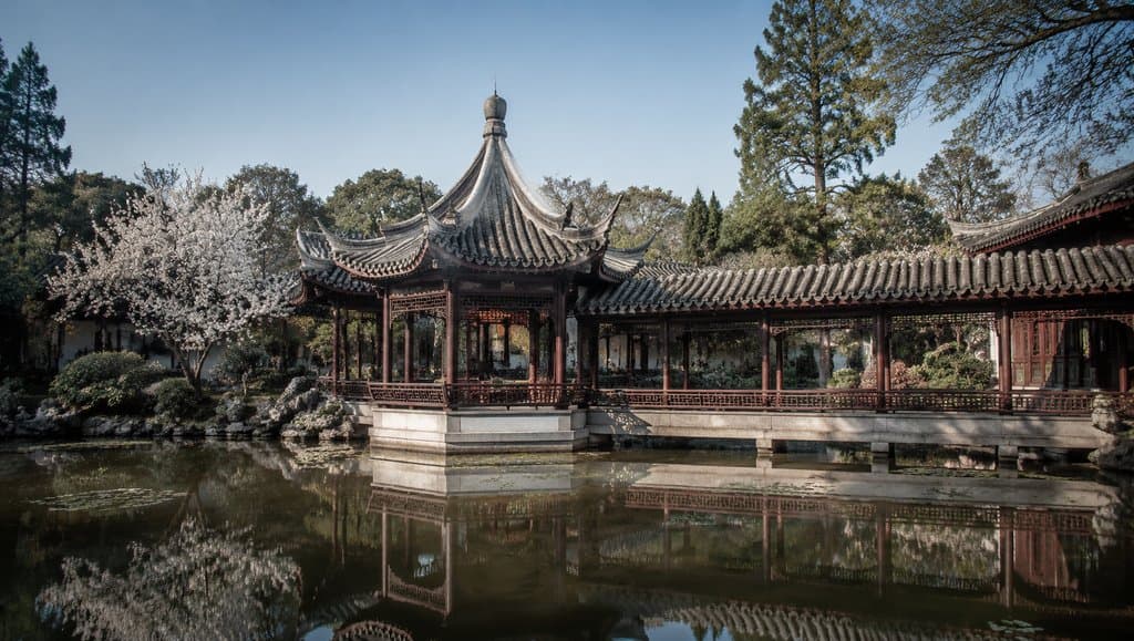 古典中式亭台水榭，飞檐攒尖屋顶，雕栏游廊倒映水中，春日樱花盛开，写实风格建筑