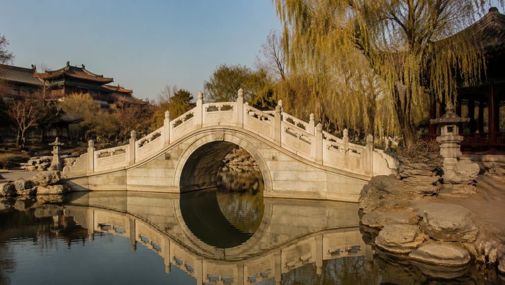 汉白玉拱桥横跨水面，雕栏精致，倒影清晰，古装宫廷风格写实建筑