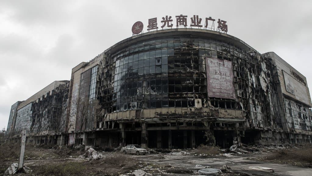 废弃商场建筑，玻璃幕墙破损，垂挂招牌，坍塌结构，末世废土风格