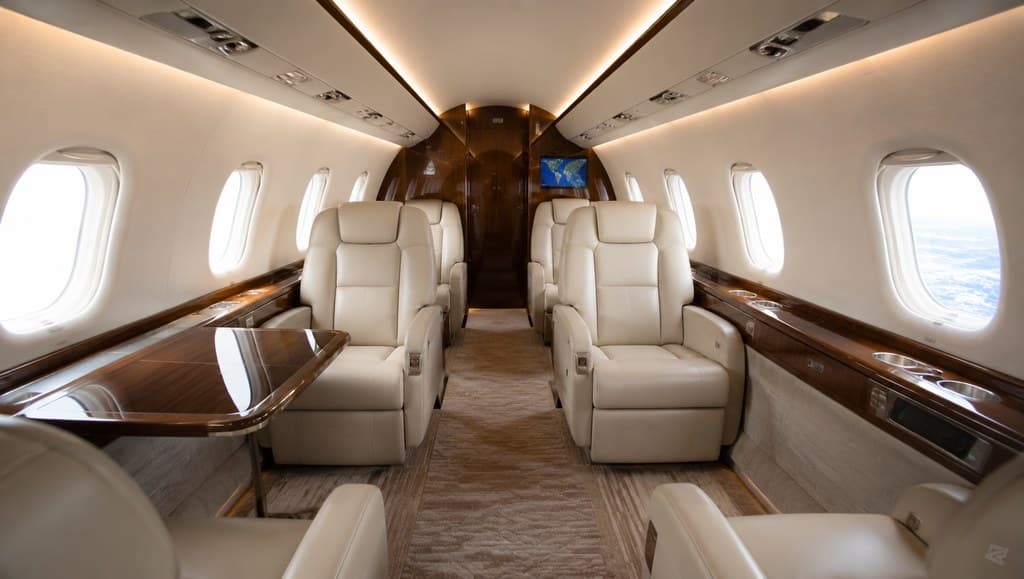 private jet cabin interior with cream leather seats and wood-trim paneling