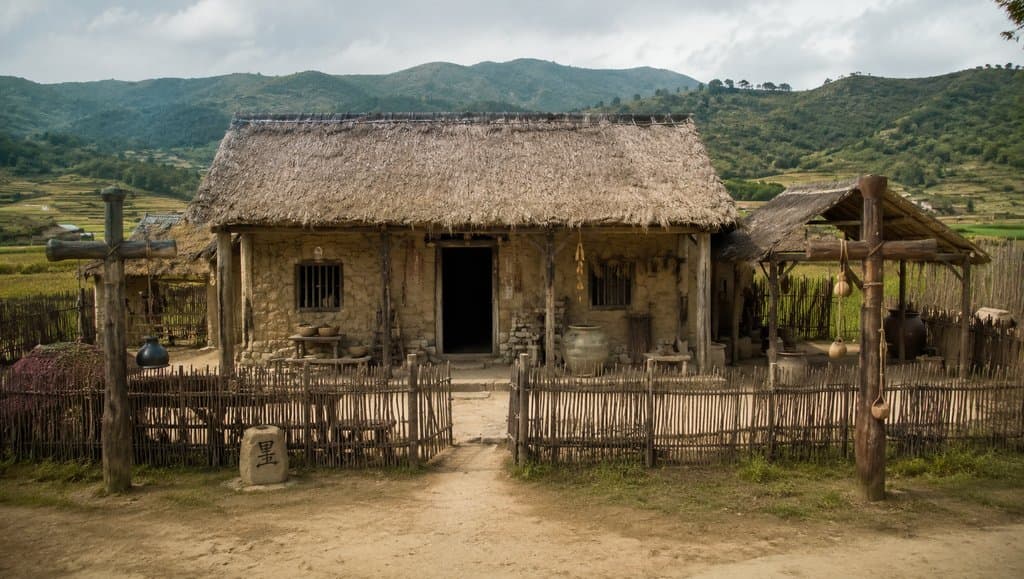 商周风格陶屋村舍，夯土墙体，茅草屋顶，篱笆院落，写实古风建筑