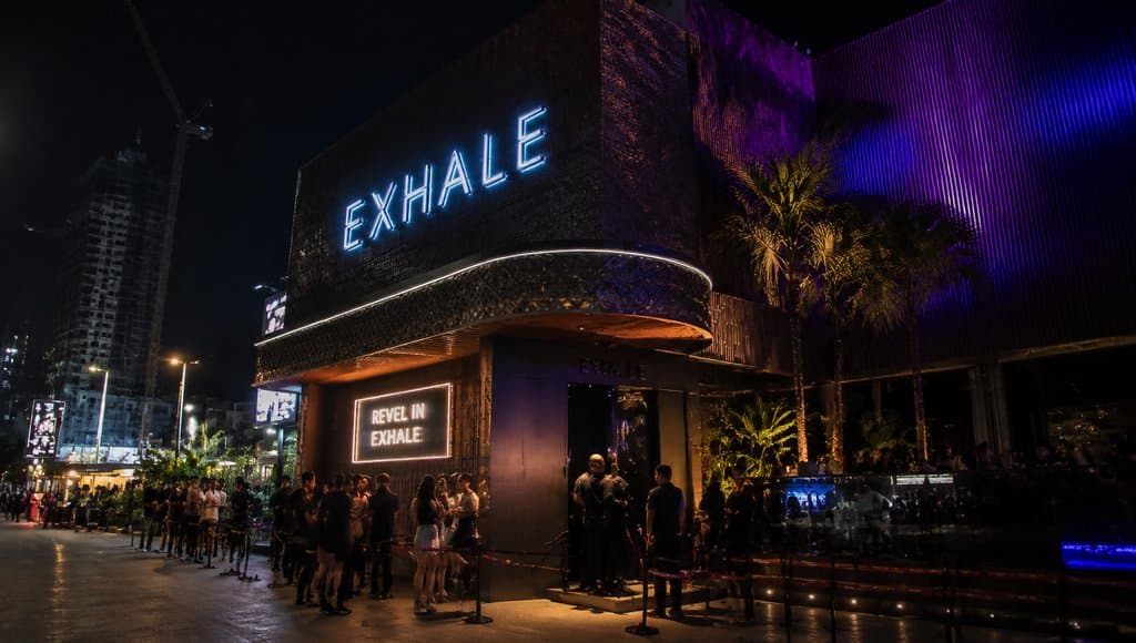 夜晚霓虹灯照亮的夜店Exhale外观，人群排队入场，现代都市建筑风格